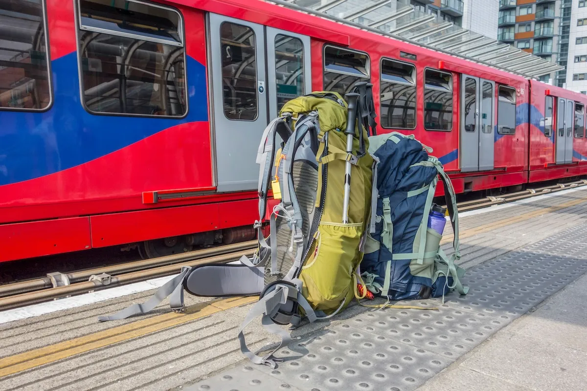 A backpacker's loaded rucksack resting on a train platform at the start of a long, budget trip